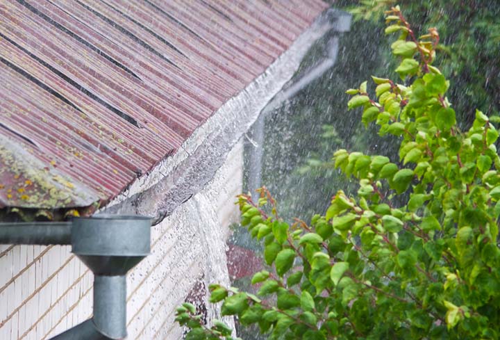 Water overflowing a sagging gutter in a rainstorm