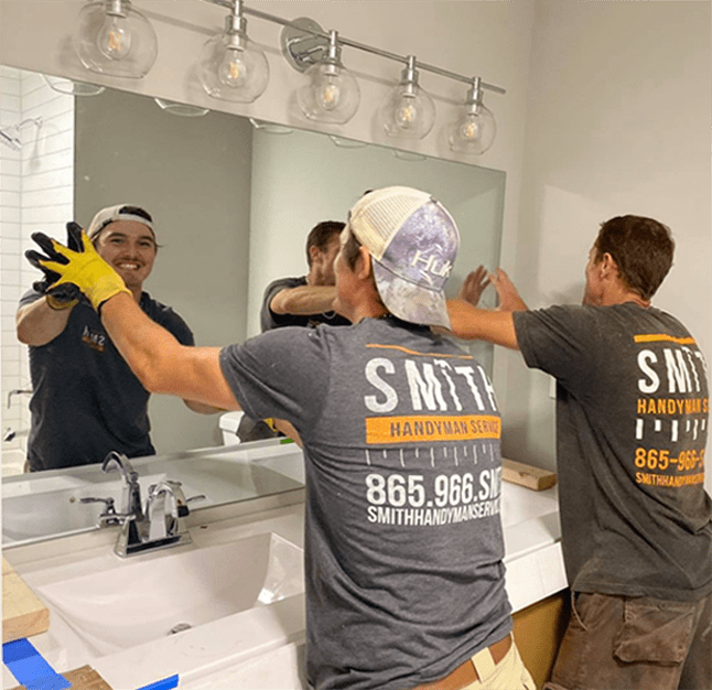 Two men putting up a mirror in a bathroom