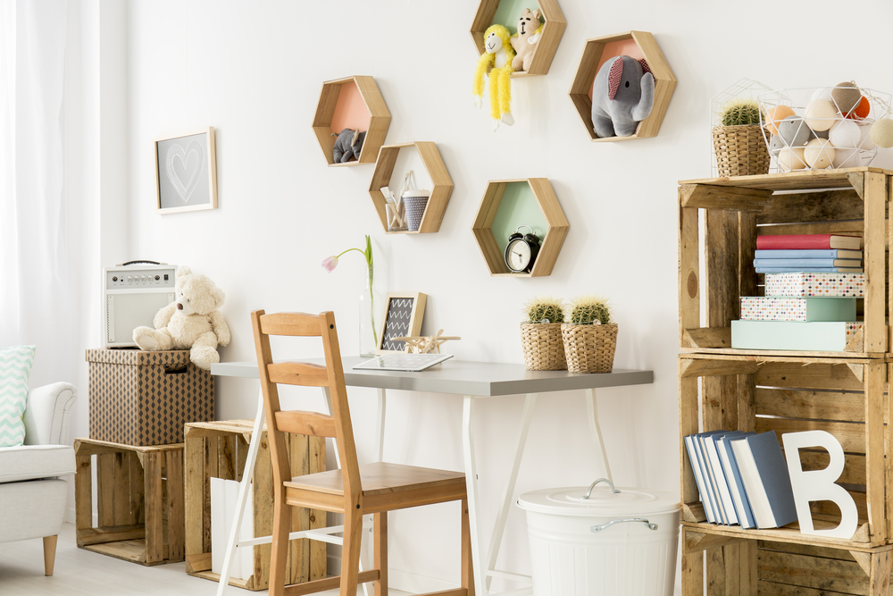 a children’s bedroom with shaped shelving on the walls above a desk