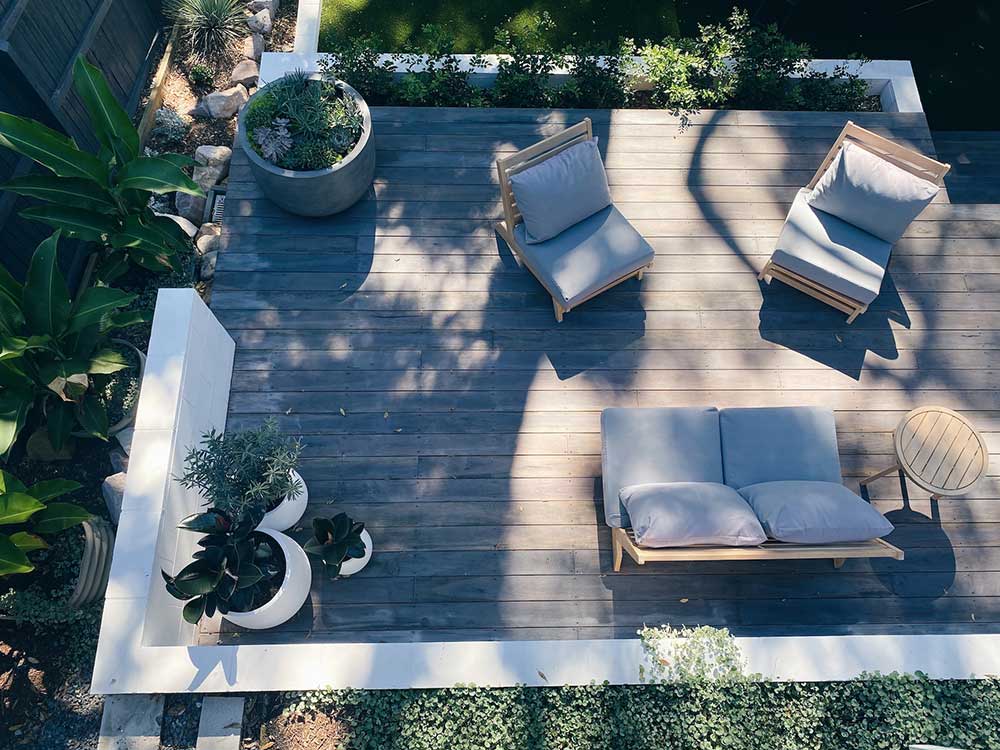 A birds-eye view of a gray wooden deck with some outdoor furniture