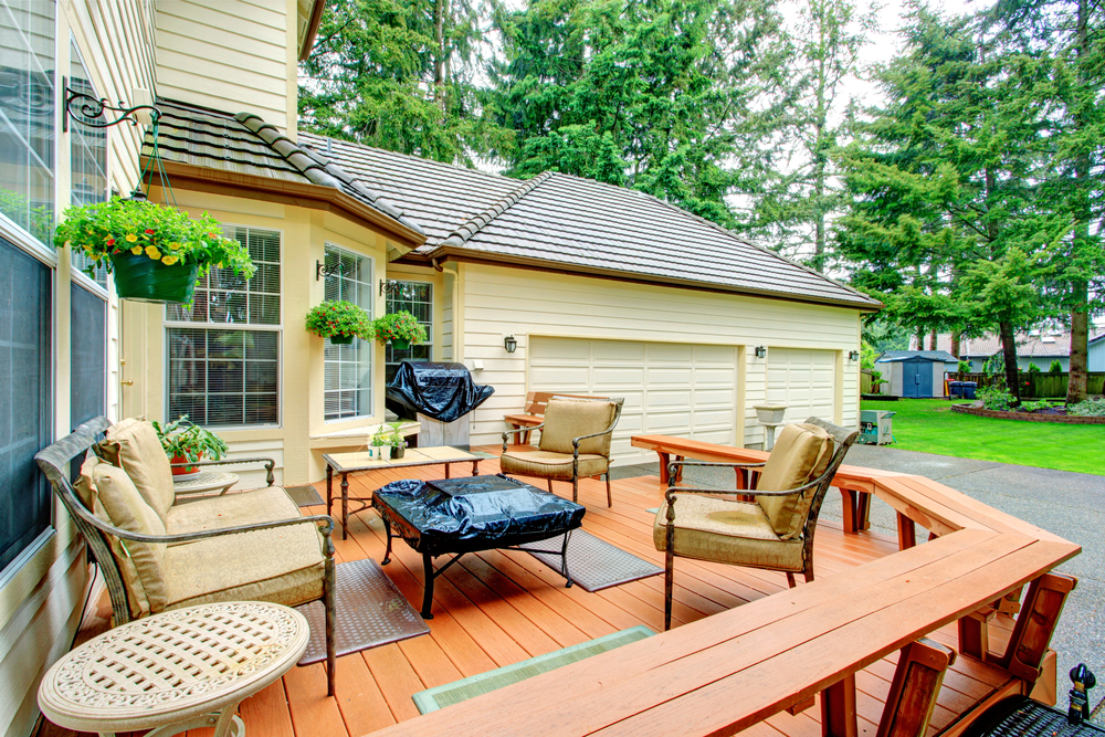 a wooden deck in the back of a house with patio furniture on it