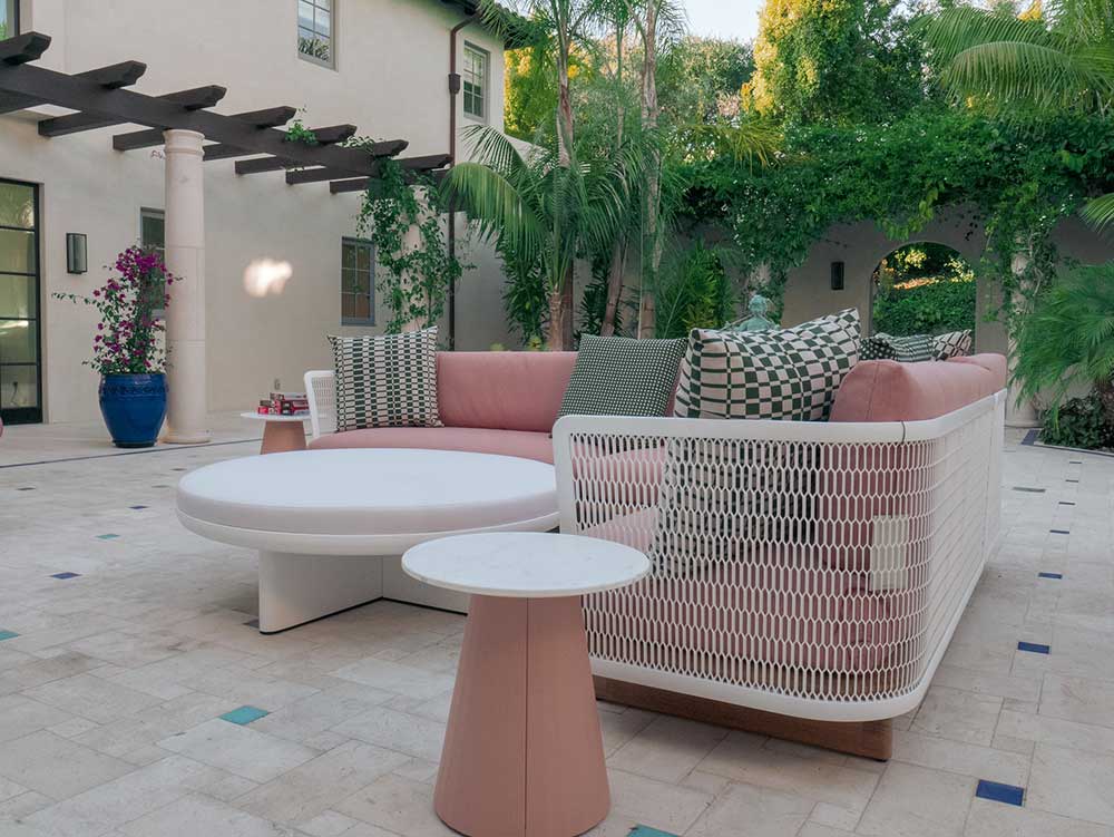 A white patio connected to a house with a pink sectional