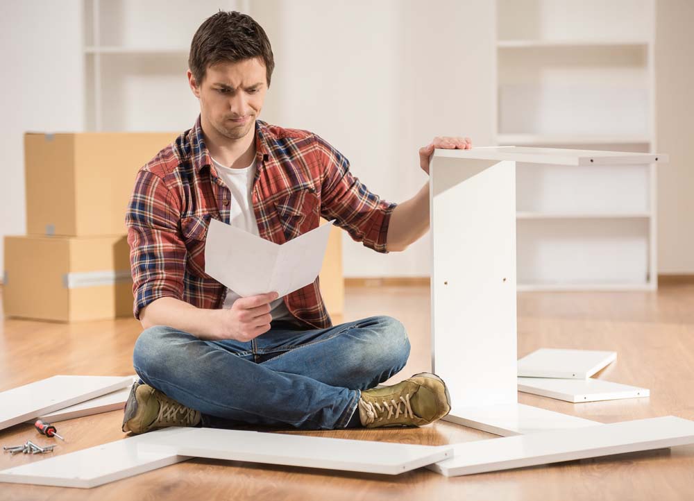 a man reading the instructions while hesitantly trying to put together furniture