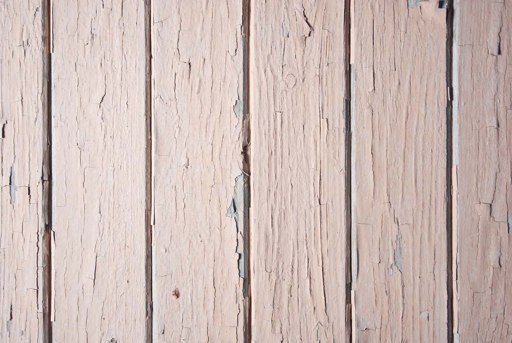 A close-up of vertical wooden siding with peeling paint.