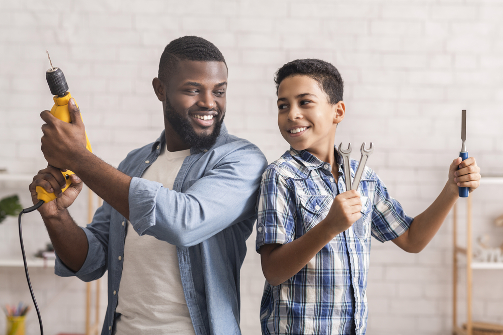 Father and son with tools kneeling next to boards