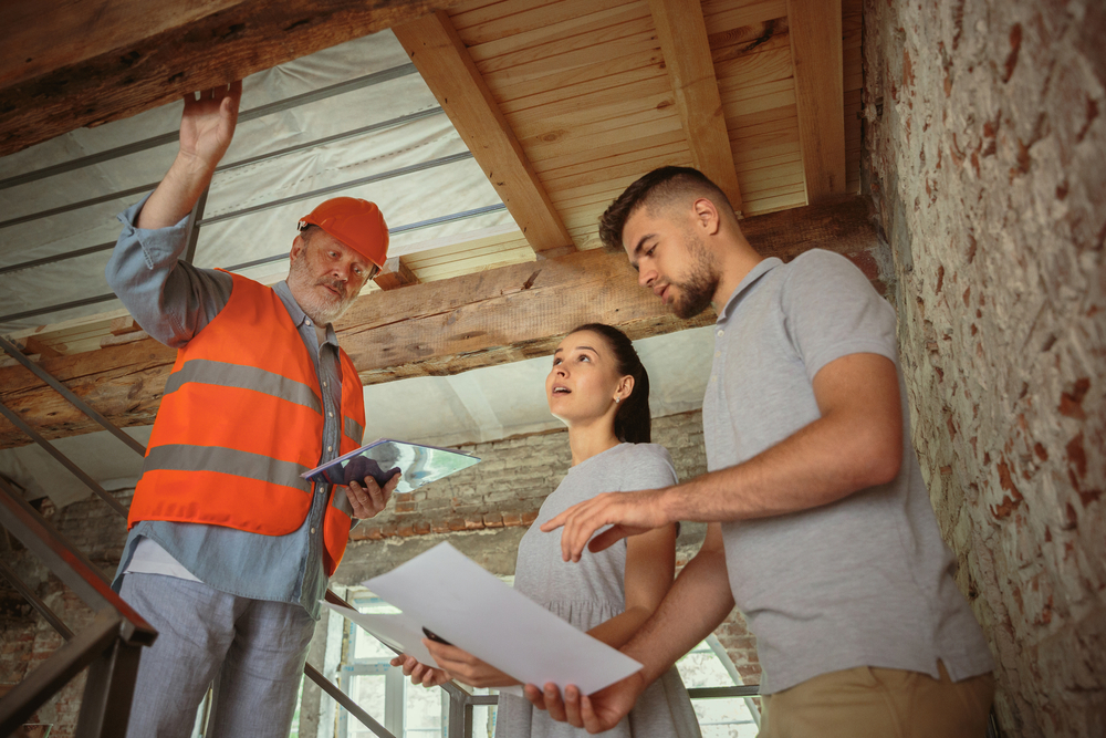 Foreman shows a house to a couple while looking at plans