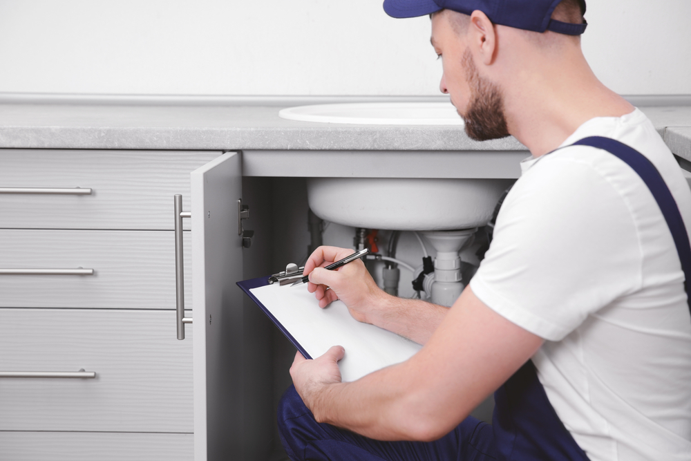 Man making a list while looking under the sink