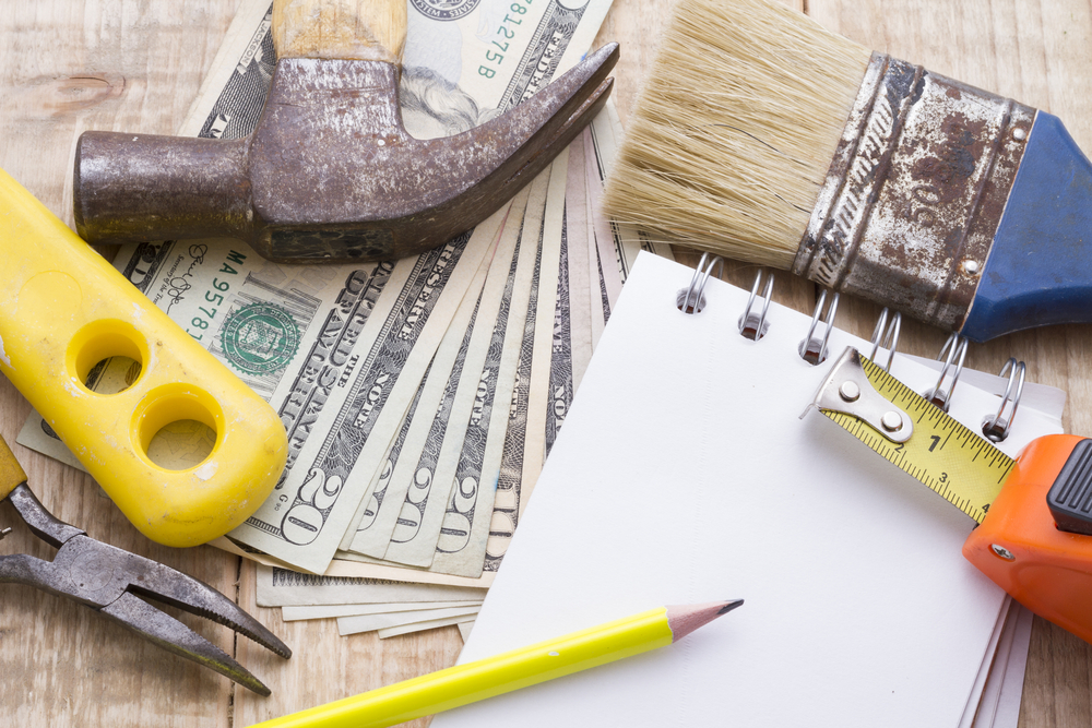 Notebook and pencil, money, and tools lying on a table